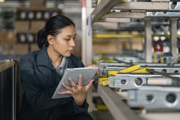 Female worker in factory warehouse on tablet